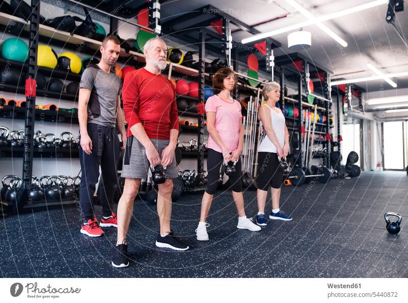 Gruppe fitter Senioren mit Personal Trainer im Fitnessstudio trainieren Gewicht Gewichte Fitnessclubs Fitnessstudios Turnhalle alte ältere heben Fitnessgerät