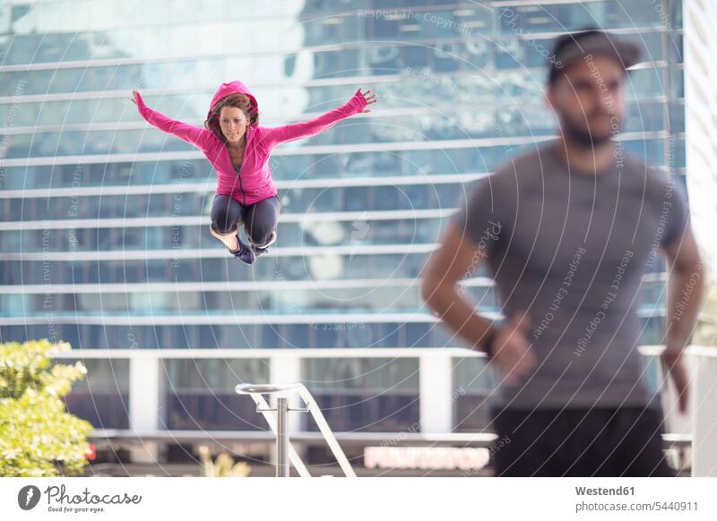 Mann rennt und Frau springt in der Stadt springen hüpfen trainieren Sportler Sprung Spruenge Sprünge Training Freizeitsport Urban städtisch Urbanität Urbanitaet