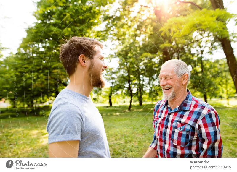 Senior-Vater und sein erwachsener Sohn lachen zusammen in einem Park Papas Väter Vati Vatis Papis Eltern Familie Familien Mensch Menschen Leute People Personen