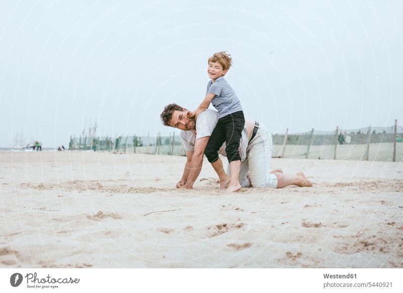 Vater und kleiner Sohn spielen gemeinsam am Strand Söhne Beach Straende Strände Beaches Papas Väter Vati Vatis Papis Kind Kinder Familie Familien Mensch