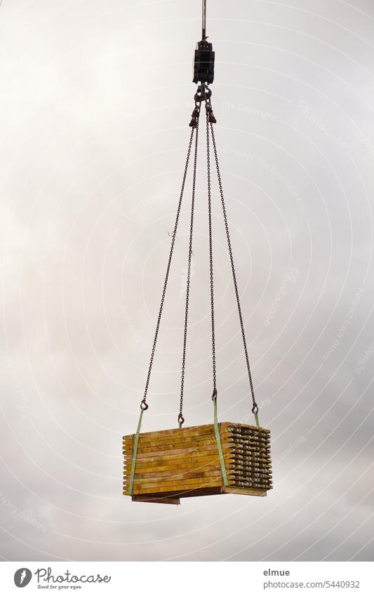 ein Stapel Holzbalken hängt an einem Kranausleger Holzstapel Holztransport Tragkraft Baustelle Transportkosten Bauholz Blog Bauholztransport Naturmaterial