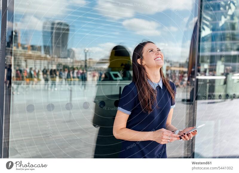 UK, London, glückliche Frau mit Smartphone in der Stadt weiblich Frauen Handy Mobiltelefon Handies Handys Mobiltelefone lächeln Erwachsener erwachsen Mensch