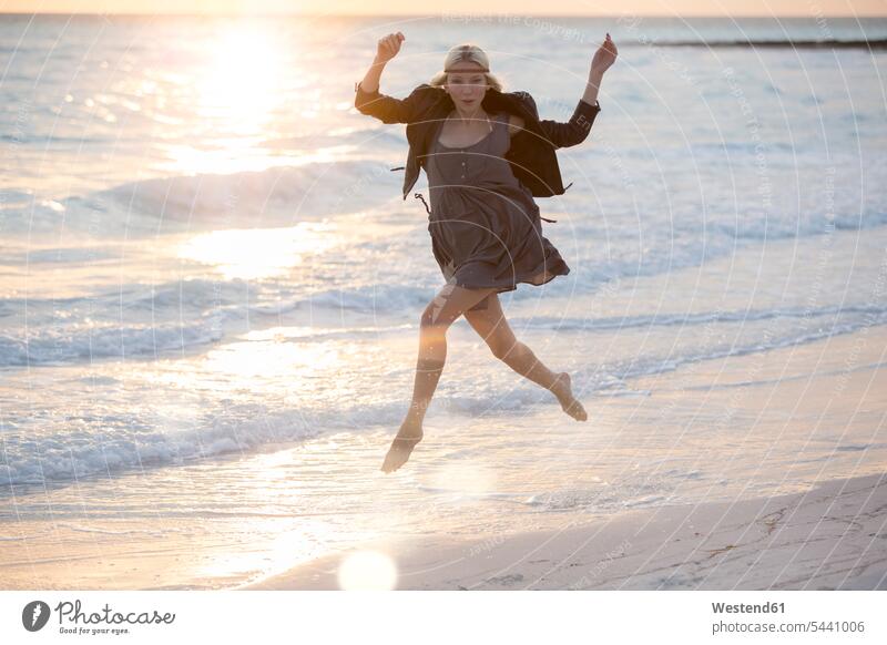 Junge Frau springt vor Freude am Strand glücklich Glück glücklich sein glücklichsein Auszeit Alles hinter sich lassen abschalten entspannen Meer Meere laufen