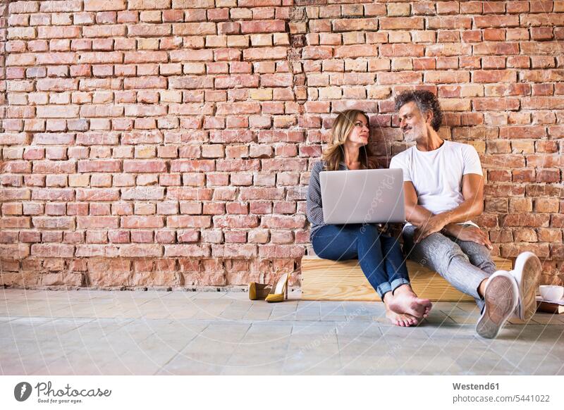 Geschäftsmann und -frau sitzen in einem Loft, benutzen einen Laptop und gründen ein Start-up-Unternehmen Geschäftsleute Geschäftspersonen Unternehmensgründung