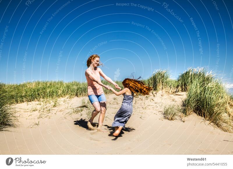 Niederlande, Zandvoort, glückliche Mutter und Tochter tanzen in den Stranddünen Spaß Spass Späße spassig Spässe spaßig Familie Familien Glück glücklich sein