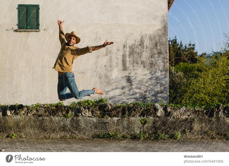 Glücklicher junger Mann springt in die Luft Luftsprung Luftsprünge einen Luftsprung machen Luftspruenge Männer männlich springen hüpfen Sprung Spruenge Sprünge