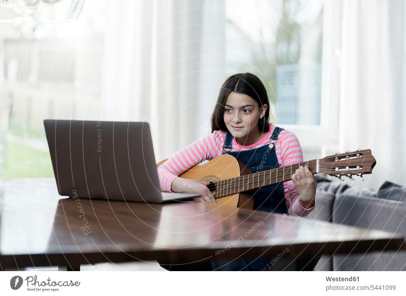 Mädchen spielt Gitarre vor dem Laptop weiblich Notebook Laptops Notebooks sitzen sitzend sitzt Gitarren Kind Kinder Kids Mensch Menschen Leute People Personen