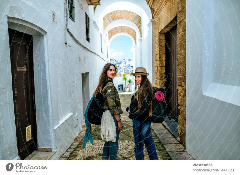 Spanien, Andalusien, Vejer de la Frontera, zwei junge Frauen gehen in der Gasse El Callejon de las Monjas Gassen Freundinnen lächeln Weg Wege Pfad Freunde