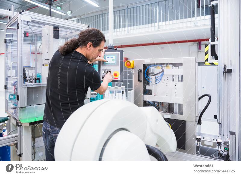 Mann bedient Montageroboter in der Fabrik arbeiten Arbeit Männer männlich Roboter Fabriken Erwachsener erwachsen Mensch Menschen Leute People Personen