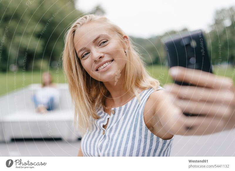 Porträt einer lächelnden jungen Frau, die ein Selfie in einem Skatepark macht Skateboardpark Skateboard-Park Skateboard Park Skaterplatz weiblich Frauen