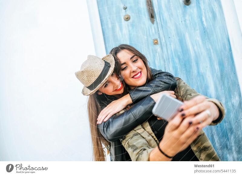 Zwei glückliche junge Frauen machen ein Selfie mit einem Smartphone Selfies lächeln Handy Mobiltelefon Handies Handys Mobiltelefone fotografieren Freundinnen