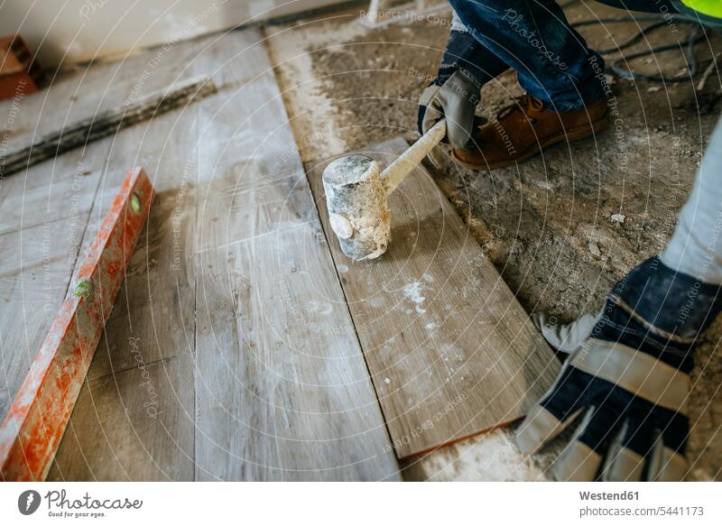 Nahaufnahme eines Bauarbeiters beim Verlegen von Bodenbelägen mit einem Hammer Baustelle Baustellen arbeiten Arbeit Konstruktion konstruieren bauen Baugewerbe