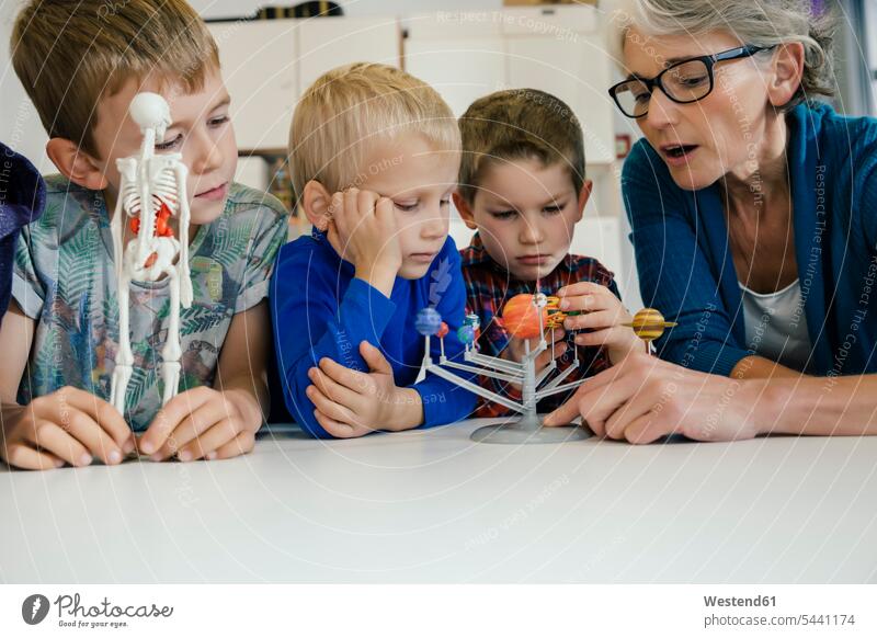 Vorschullehrerin erklärt Jungen im Kindergarten das Sonnensystemmodell Skelett Skelette ansehen Kindergaerten Kindergärten Kids Erzieherin Erzieherinnen Modell
