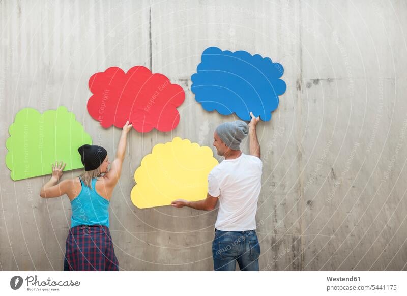 Mann und Frau befestigen bunte Wolkenformen an Betonwand anbringen farbig mehrfarbig Männer männlich Betonwände Betonwaende weiblich Frauen Form Formen Farbe