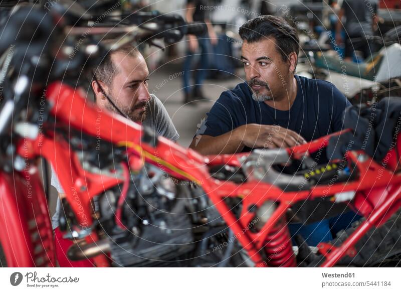 Zwei Mechaniker arbeiten gemeinsam am Motorrad in der Werkstatt Motorräder reparieren Reparatur Arbeit Kollegen Arbeitskollegen Monteur Kraftfahrzeug