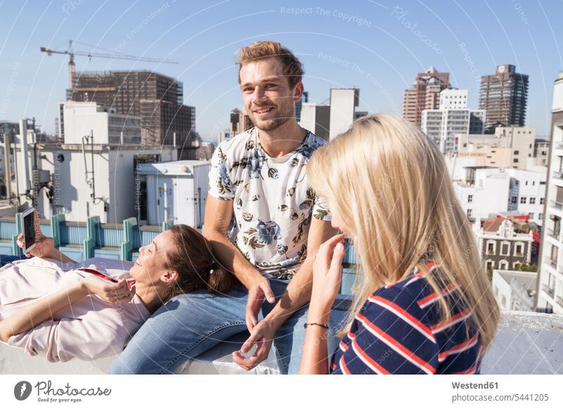 Freunde treffen sich im Sommer auf einer Dachterrasse, Frau mit Smartphone Sommerzeit sommerlich Teilen Sharing Dachterrassen iPhone Smartphones sprechen reden