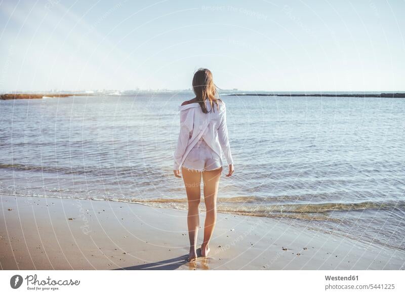Rückenansicht einer Frau am Strand mit Blick auf das Meer Beach Straende Strände Beaches weiblich Frauen Erwachsener erwachsen Mensch Menschen Leute People