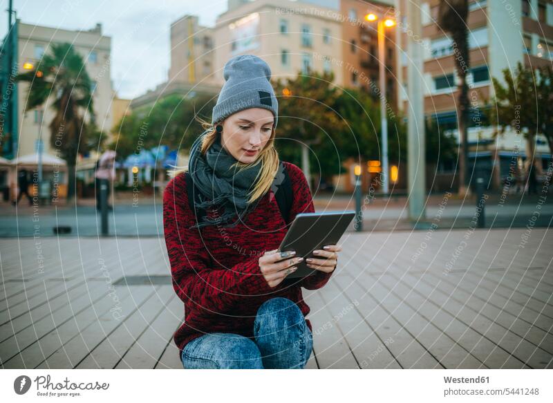 Spanien, Barcelona, junge Frau, die im Winter draußen eine Tablette benutzt weiblich Frauen Tablet Computer Tablet-PC Tablet PC iPad Tablet-Computer sitzen
