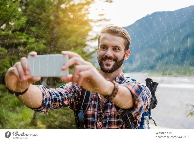 Porträt eines lächelnden jungen Wanderers, der ein Selfie mit seinem Handy macht Portrait Porträts Portraits Selfies wandern Wanderung Smartphone iPhone