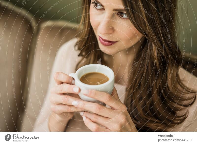 Porträt einer Frau, die auf einer Couch sitzt und eine Tasse weißen Kaffee trinkt trinken weiblich Frauen Erwachsener erwachsen Mensch Menschen Leute People