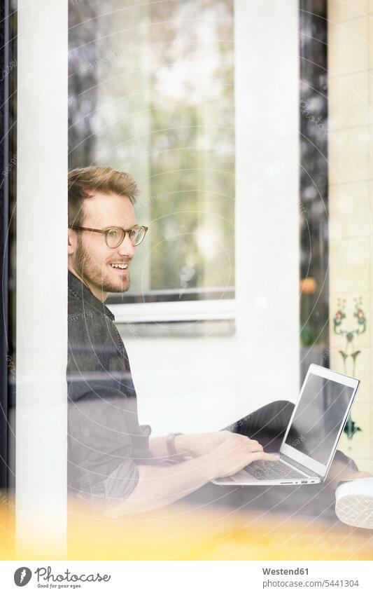 Porträt eines lächelnden Mannes mit Laptop am Fenster Notebook Laptops Notebooks Männer männlich Portrait Porträts Portraits Computer Rechner Erwachsener