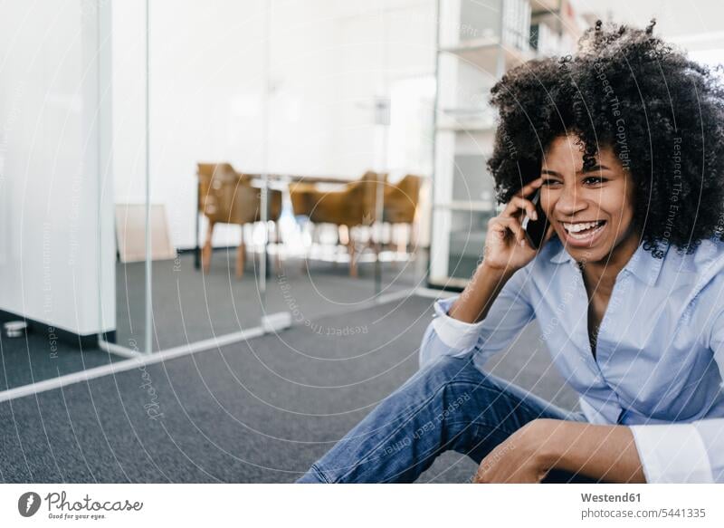 Lachende junge Frau am Mobiltelefon im Büro Handy Handies Handys Mobiltelefone lachen telefonieren anrufen Anruf telephonieren weiblich Frauen Telefon