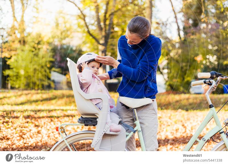 Mutter und Tochter fahren Fahrrad, das Baby trägt einen Helm und sitzt im Kindersitz Fahrradhelm Radhelm Fahrradhelme Bikes Fahrräder Räder Mami Mutti Mütter