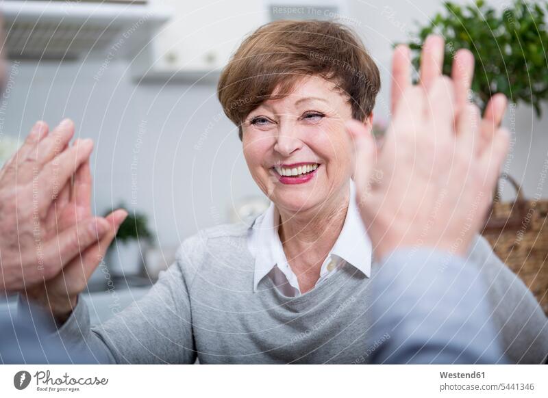 Lächelnde ältere Frau gibt Mann High Five fröhlich Fröhlichkeit Frohsinn Heiterkeit Unbeschwert Sorglos abklatschen Senioren alte Freude freuen Erwachsene