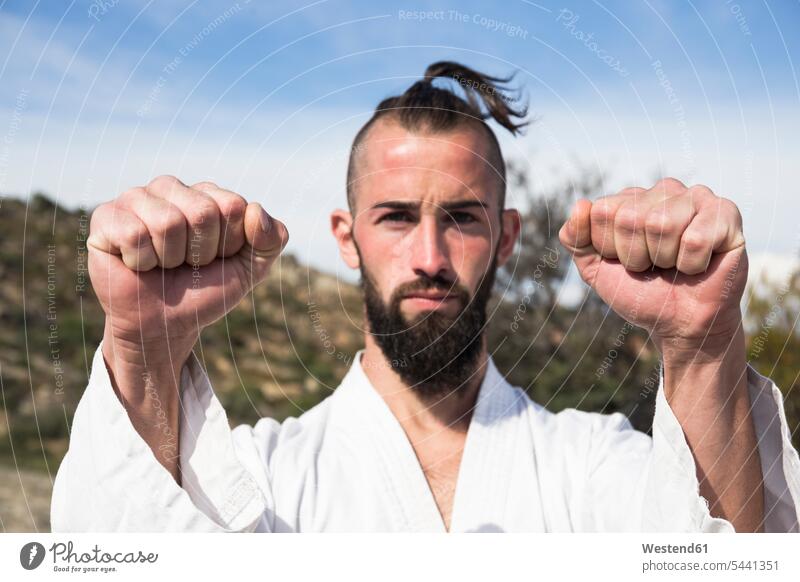 Porträt eines Mannes, der eine Kampfkunst-Pose im Freien einnimmt kämpfen kaempfen Faust Männer männlich trainieren Kampfsport Kampfsportart Kampfsportarten