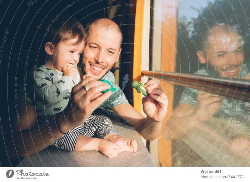 Vater spielt mit seinem kleinen Mädchen, während er mit dem Zug reist Baby Babies Babys Säuglinge Kind Kinder Papas Väter Vati Vatis Papis Fenster Bahnen Züge
