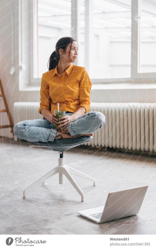 Junge Frau sitzt in ihrer neuen Wohnung mit einem Laptop weiblich Frauen Stuhl Stuehle Stühle Notebook Laptops Notebooks Umzug umziehen Eistee Eistees trinken