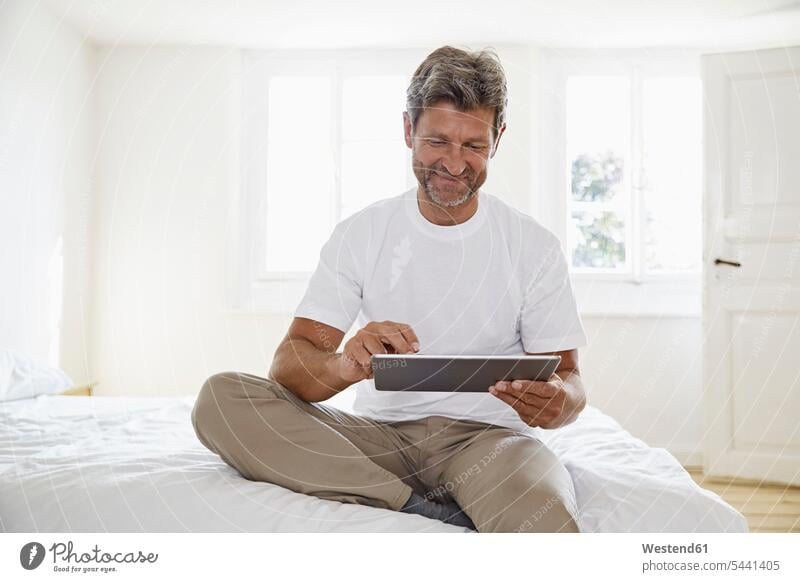 Porträt eines reifen Mannes mit digitalem Tablett im Schlafzimmer Männer männlich sitzen sitzend sitzt Tablet Computer Tablet-PC Tablet PC iPad Tablet-Computer