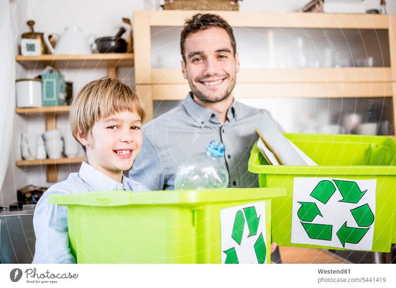 Vater und Sohn zu Hause mit Abfallboxen Müll Mist Recycling Ökologie Wiederverwertung recyceln lächeln Söhne Papas Väter Vati Vatis Papis Zuhause daheim Familie