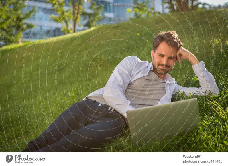 Mann liegt mit seinem Laptop im Gras Notebook Laptops Notebooks Entspannung entspannt Entspannen relaxen entspannen Wiese Wiesen Männer männlich Park
