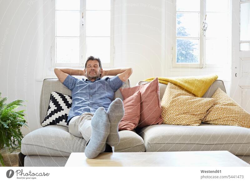 Mann sitzt zu Hause auf dem Sofa und entspannt sich Männer männlich ausruhen Rast Erholung erholen Zuhause daheim bequem sitzen sitzend Entspannung Entspannen