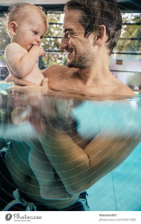 Vater hält Baby in der Schwimmhalle Babies Babys Säuglinge Kind Kinder Schwimmbad Schwimmbaeder Schwimmbäder Papas Väter Vati Vatis Papis lächeln halten
