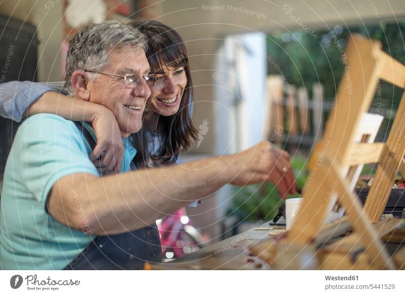 Lächelnde Frau umarmt Malerei eines älteren Mannes Senior ältere Männer älterer Mann Senioren Tochter Töchter malen lächeln umarmen Umarmung Umarmungen