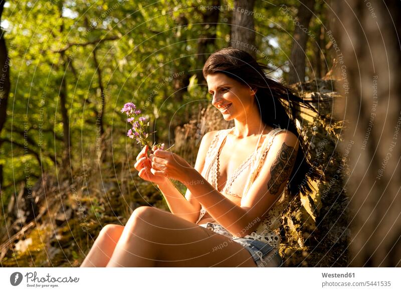 Junge Frau in waldgebundenem Blumenstrauss Blüte Wald Forst Wälder entspannt entspanntheit relaxt weiblich Frauen Entspannung relaxen entspannen Erwachsener