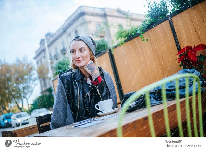 Junge tätowierte Frau sitzt in Straßencafé Straßencafe Straßencafes Strassencafe Strassencafes weiblich Frauen Cafe Kaffeehaus Bistro Cafes Café Cafés
