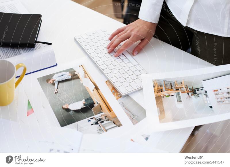 Nahaufnahme einer Frau, die eine Fotografie hält und im Büro eine Computertastatur benutzt Schreibtisch Arbeitstisch Schreibtische Geschäftsfrau Geschäftsfrauen