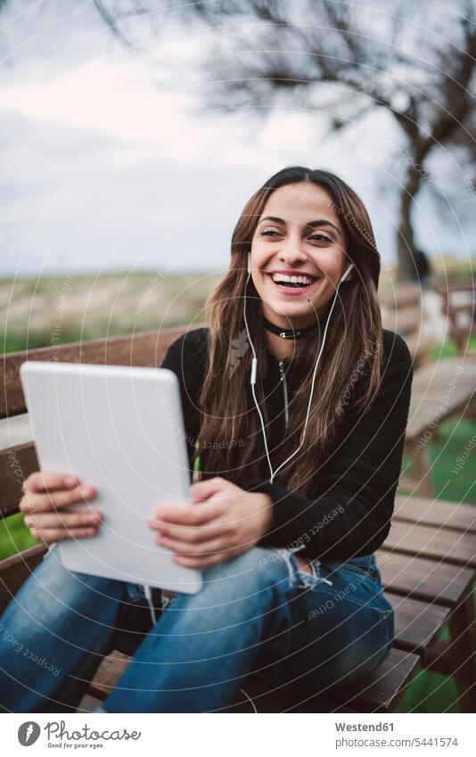 Porträt einer lächelnden jungen Frau, die ein Tablett mit Kopfhörern im Freien benutzt weiblich Frauen Tablet Computer Tablet-PC Tablet PC iPad Tablet-Computer