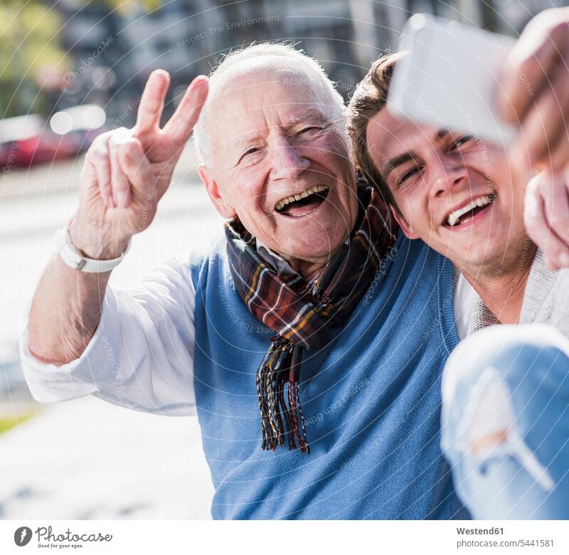 Glücklicher älterer Mann und erwachsener Enkel machen ein Selfie Enkelsöhne Enkelsohn lächeln Selfies glücklich glücklich sein glücklichsein Handy Mobiltelefon