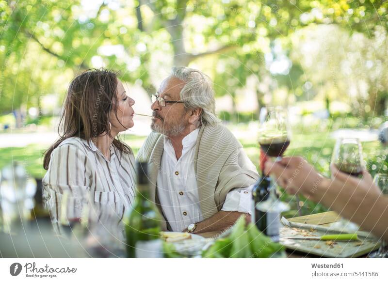 Älteres Ehepaar teilt Spaghetti am Tisch im Freien küssen Küsse Kuss Paar Pärchen Paare Partnerschaft Spagetti Mensch Menschen Leute People Personen Pasta Nudel