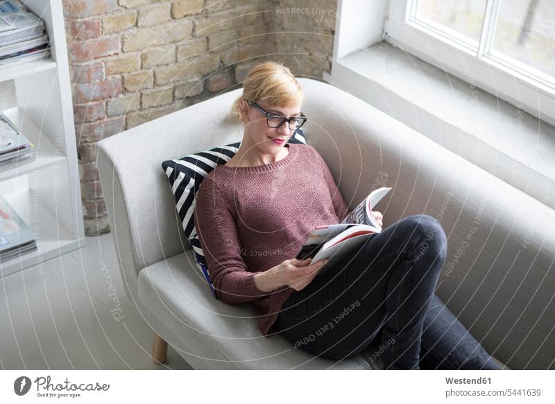 Frau sitzt auf Couch, liest Buch weiblich Frauen Entspannung entspannt Entspannen relaxen entspannen Bücher Zuhause zu Hause daheim Sofa Couches Liege Sofas