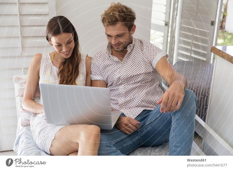 Lächelndes junges Paar, das sich einen Laptop teilt Pärchen Paare Partnerschaft lächeln Notebook Laptops Notebooks Mensch Menschen Leute People Personen