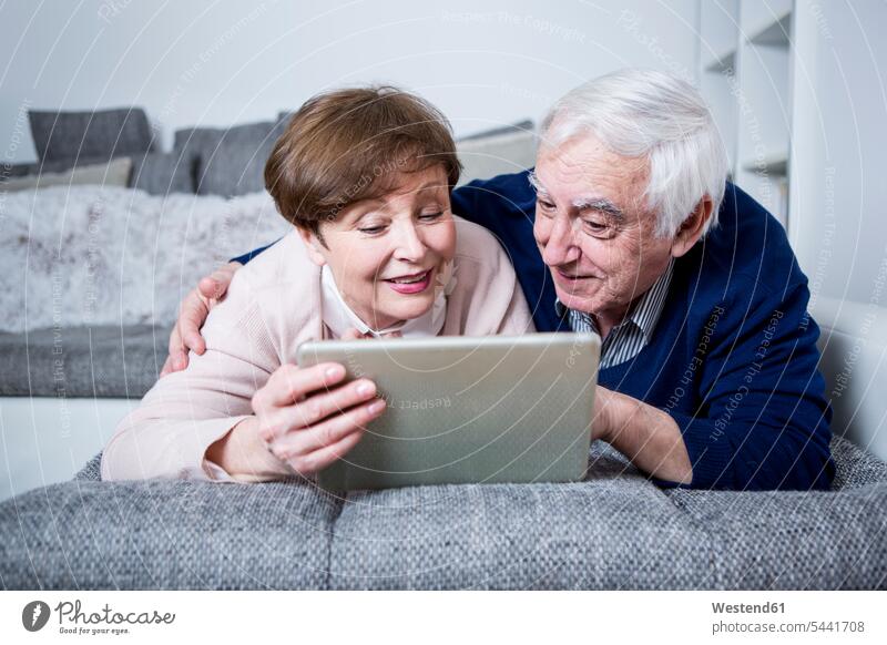 Älteres Paar liegt auf der Couch und benutzt ein digitales Tablett Sofa Couches Liege Sofas Tablet Computer Tablet-PC Tablet PC iPad Tablet-Computer Senioren