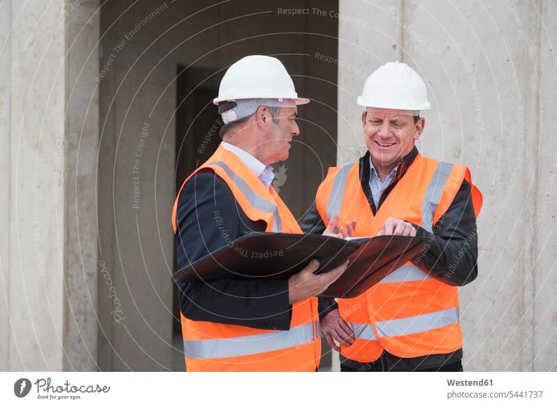 Zwei Männer in Sicherheitswesten unterhalten sich auf der Baustelle arbeiten Arbeit sprechen reden Mann männlich Architekt Architekten Baustellen Erwachsener