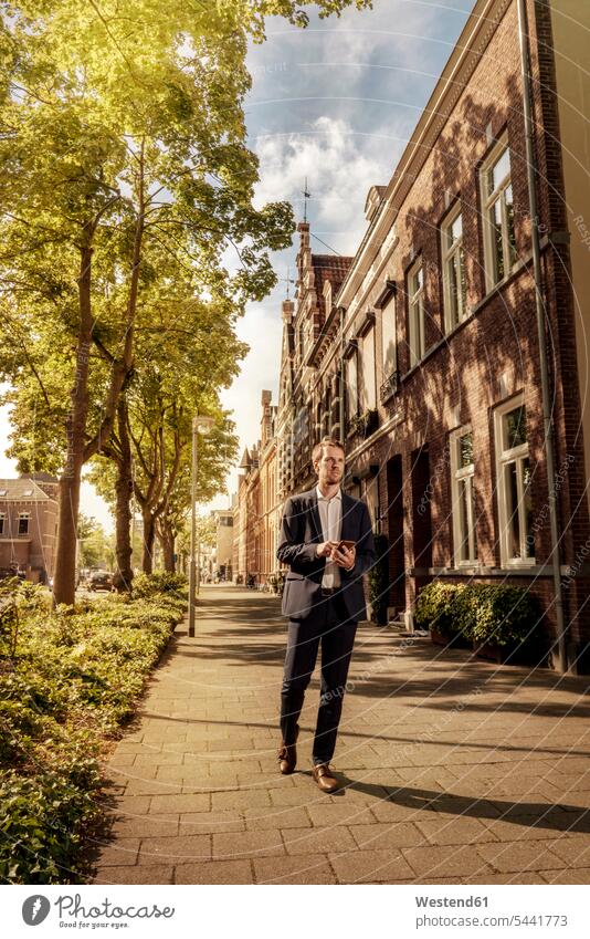 Niederlande, Venlo, Geschäftsmann mit Handy auf dem Gehsteig Gehwege Gehsteige Bürgersteige Straßenpflaster Trottoir gehen gehend geht Stadt staedtisch
