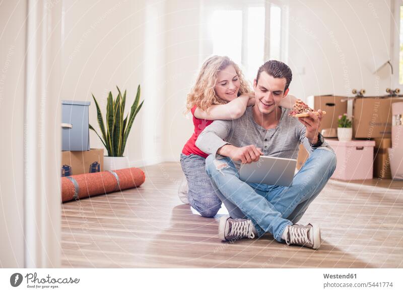 Junges Paar in neuer Wohnung sitzt mit Tablette auf dem Boden wohnen Wohnungen Pärchen Paare Partnerschaft Wohnen Mensch Menschen Leute People Personen Umzug