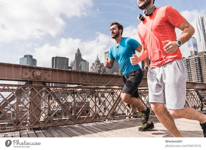 USA, New York City, zwei Männer laufen auf der Brooklyn Brige Kopfhörer Kopfhoerer Joggen Jogging Mann männlich Brücke Bruecken Brücken rennen Fitness fit